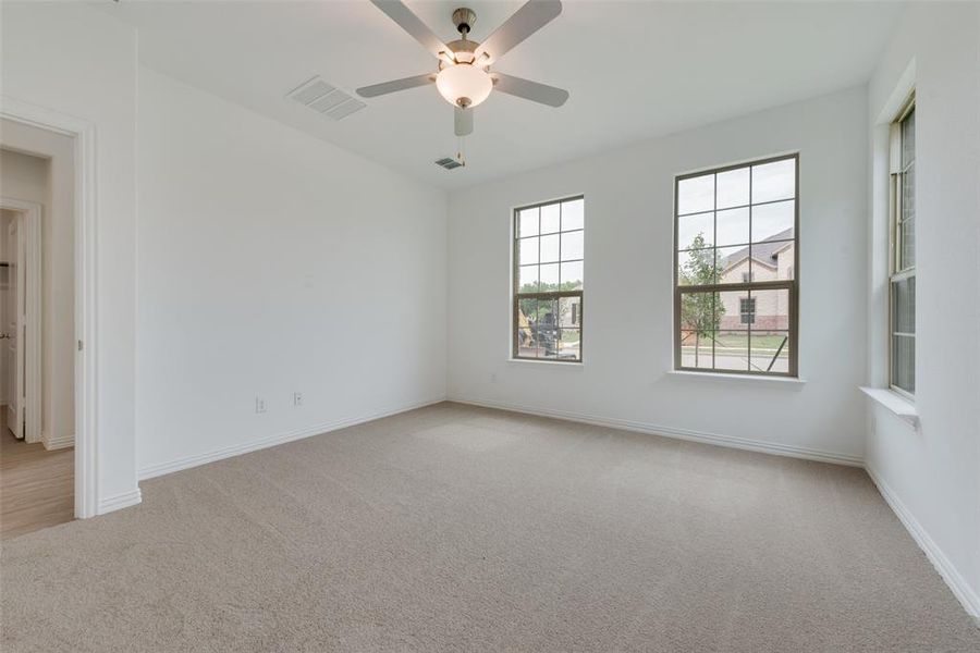 Empty room with ceiling fan and light carpet