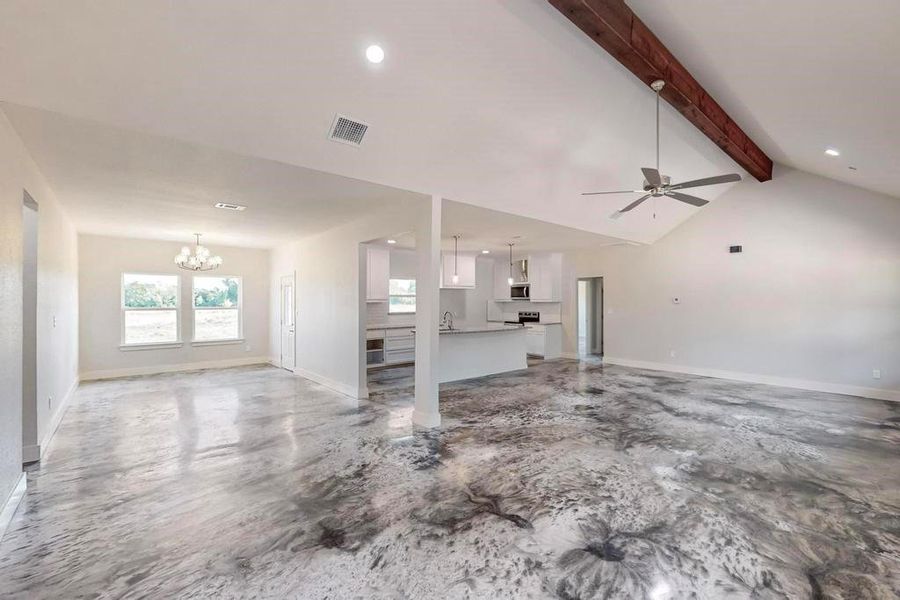 Unfurnished living room with vaulted ceiling with beams and ceiling fan with notable chandelier