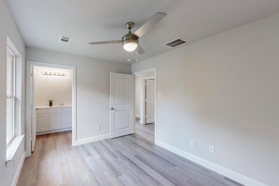 Unfurnished bedroom with connected bathroom, light hardwood / wood-style floors, and ceiling fan