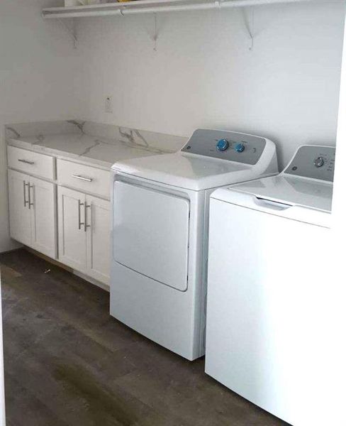 Clothes washing area with cabinets, dark wood-type flooring, and washer and clothes dryer