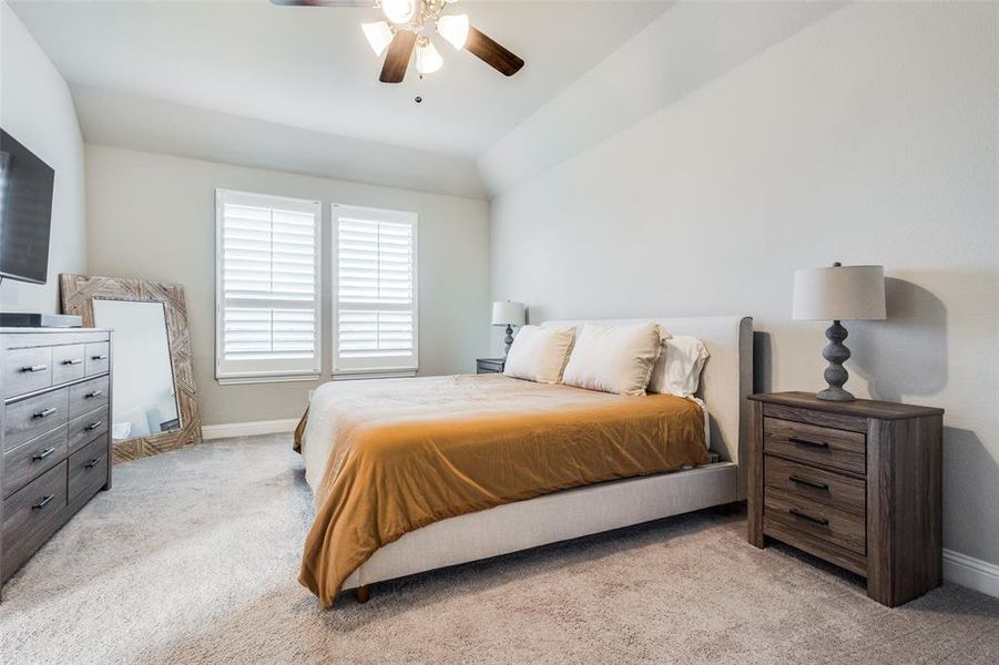 Carpeted bedroom with lofted ceiling and ceiling fan