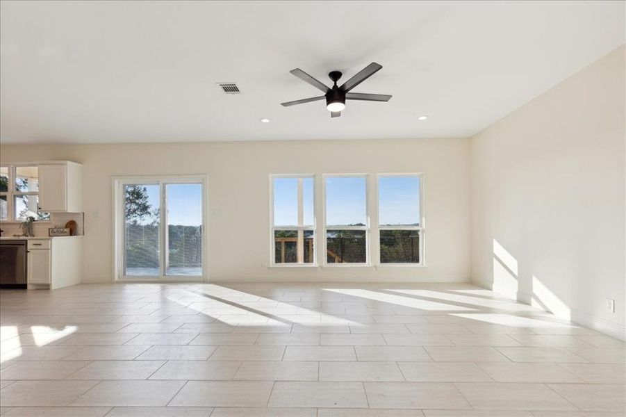 Unfurnished living room featuring plenty of natural light, ceiling fan, and light tile floors