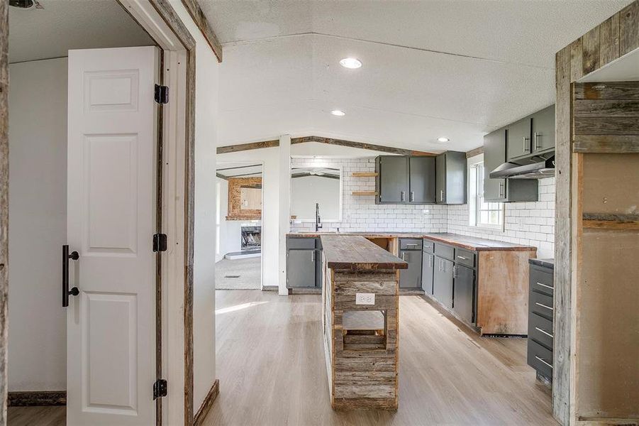 Kitchen featuring gray cabinets, butcher block counters, backsplash, and light hardwood / wood-style floors