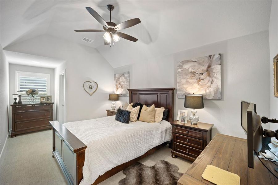 Carpeted bedroom featuring vaulted ceiling and ceiling fan