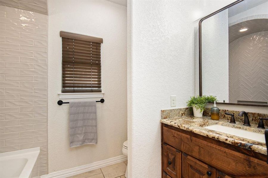 Bathroom with toilet, vanity, and tile patterned flooring