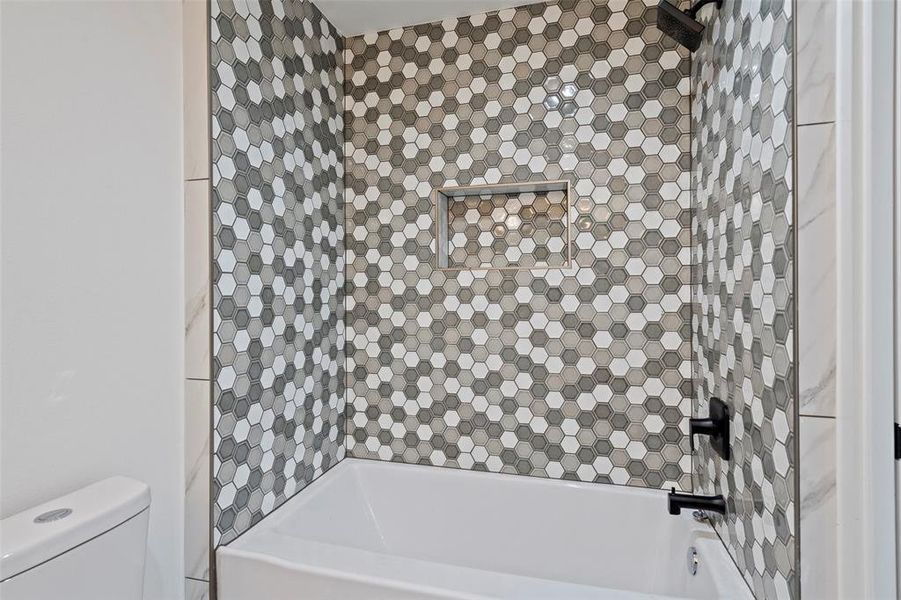 Bathroom with tiled shower / bath combo and toilet
