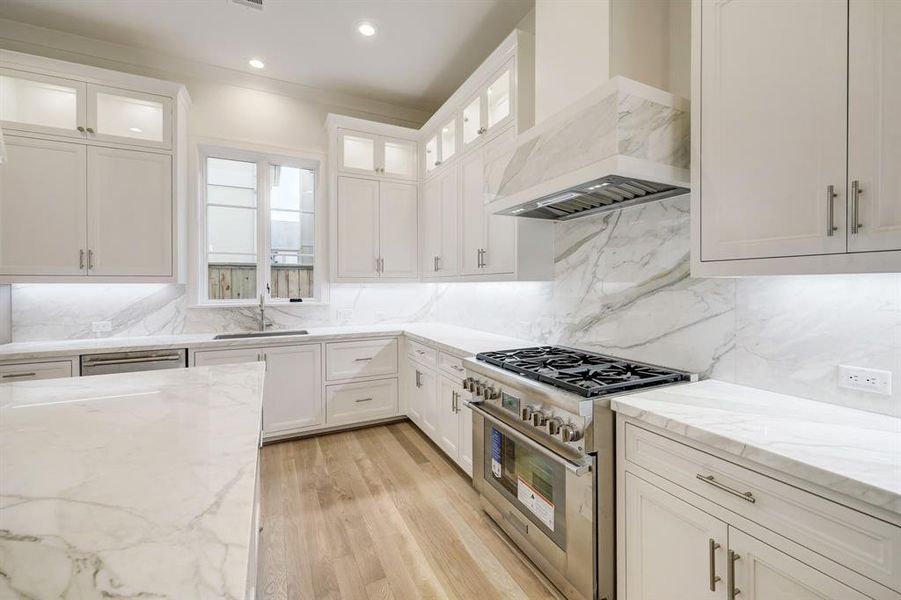 Kitchen features Thermador stainless appliances including this 6 burner gas range that is surrounded by marble countertops and marble backsplash.  Notice the vent hood! WOW!  You will also love the window over the sink!