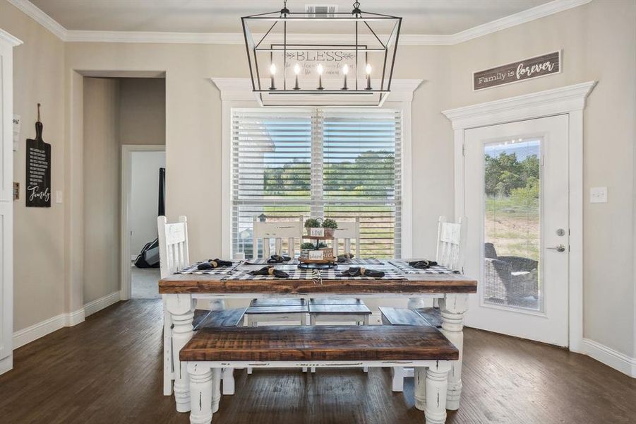 Dining room with an inviting chandelier, ornamental molding, and dark hardwood / wood-style flooring