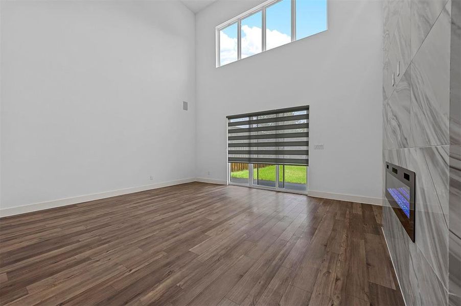 Unfurnished living room with wood-type flooring and a towering ceiling