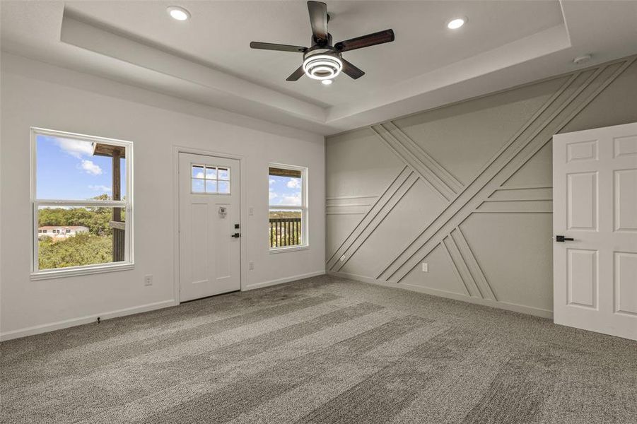 Entryway with carpet flooring, ceiling fan, and a tray ceiling