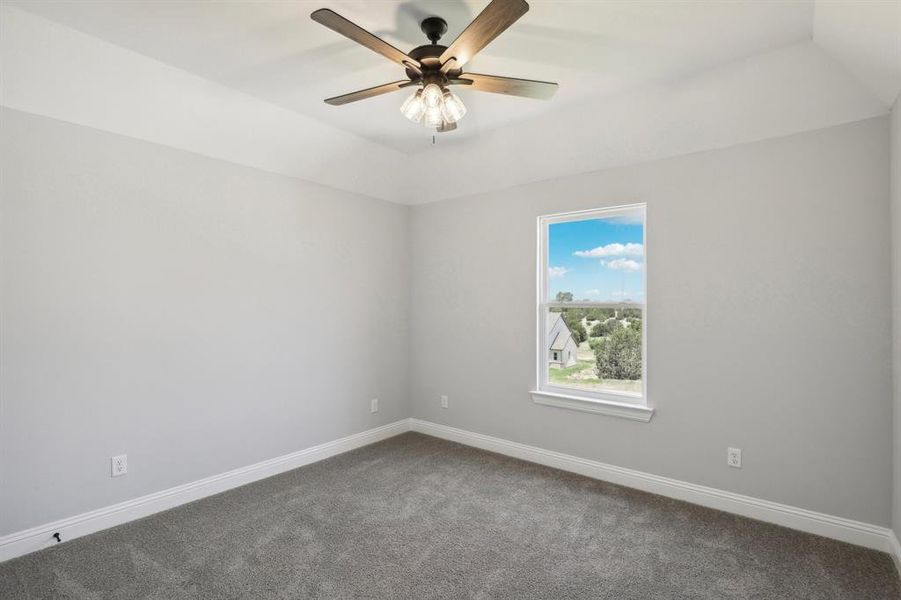 Empty room with ceiling fan and dark carpet