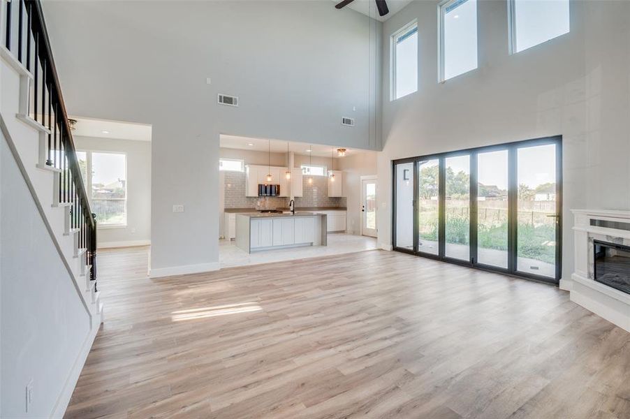 Unfurnished living room featuring light wood-type flooring, a high ceiling, ceiling fan, and sink