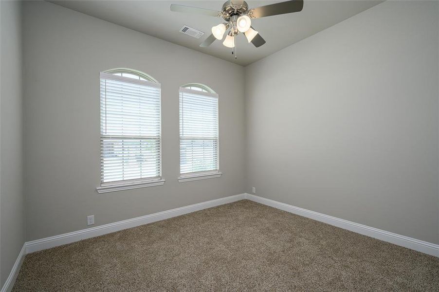 Carpeted empty room with a wealth of natural light and ceiling fan