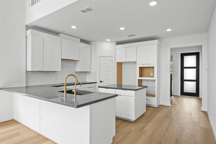 The modern white kitchen adorned with sleek dark grey countertops. This striking contrast creates a timeless aesthetic, while providing a perfect blend of sophistication and functionality. Experience culinary excellence in this stylish space, where every detail is meticulously crafted to inspire and delight.