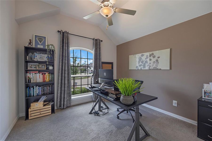 Carpeted home office featuring ceiling fan and vaulted ceiling