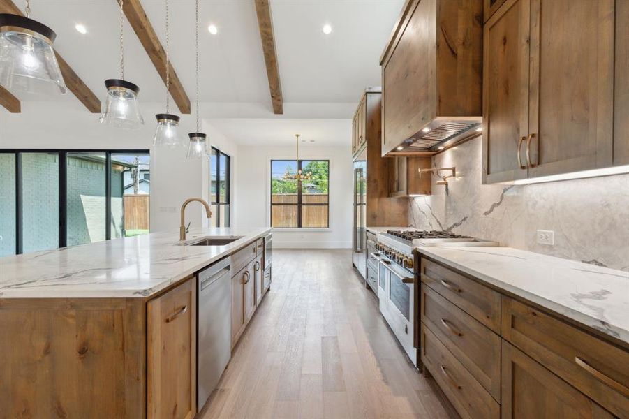 Kitchen featuring custom exhaust hood, vaulted ceilings and wood beams