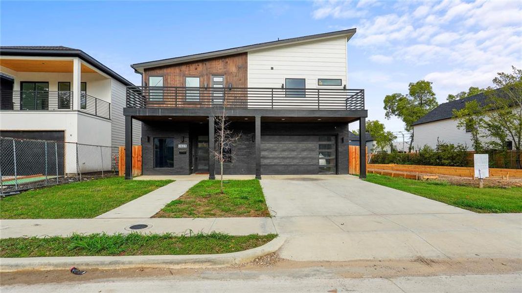 Contemporary house with a balcony, a garage, and a front yard