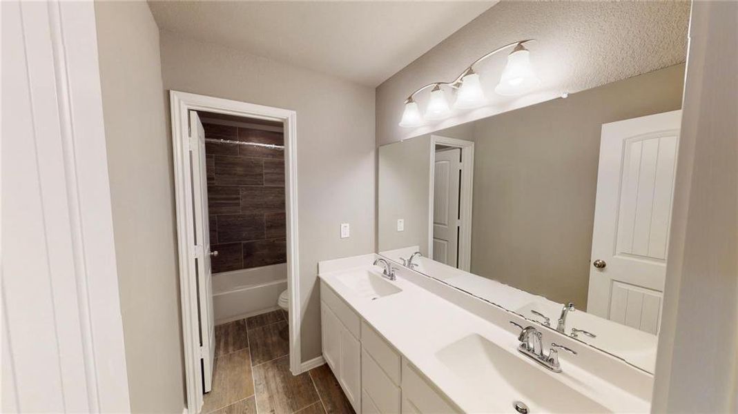 Featuring a double vanity with sleek faucets and contemporary light fixtures, this bathroom combines style and functionality. The ample counter space and storage options make it convenient for daily use. This is a picture of an Elise Floor Plan with another Saratoga Homes.