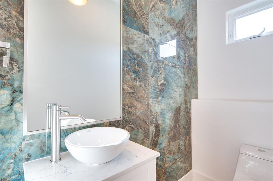 Bathroom featuring toilet, vanity, and tile walls