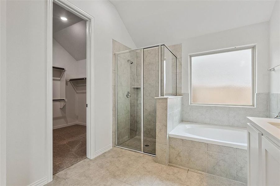 Bathroom with tile flooring, separate shower and tub, and lofted ceiling