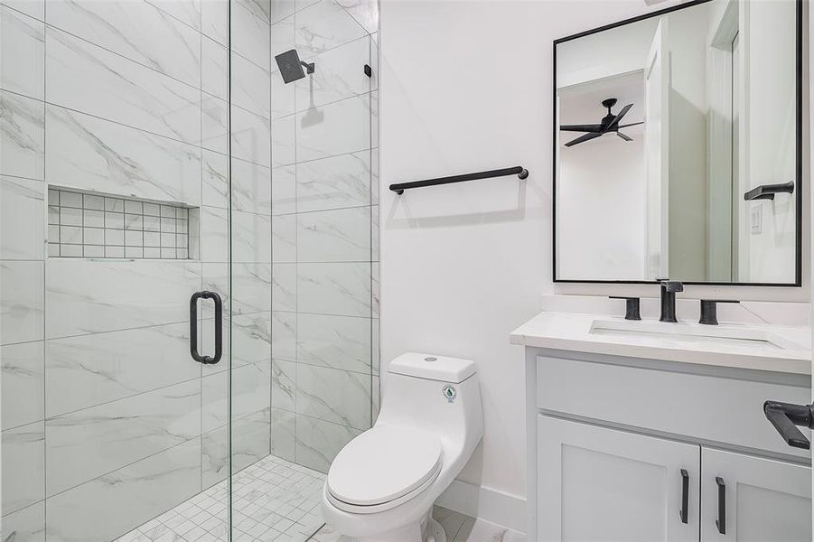 Guest room bathroom featuring toilet, an enclosed shower, and vanity