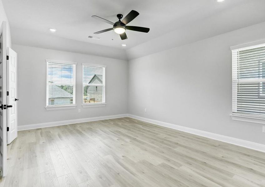 Spacious master bedroom with large windows, a ceiling fan, and wood flooring.