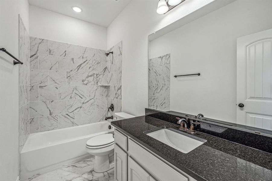 Full bathroom with vanity, tiled shower / bath, toilet, and tile patterned floors
