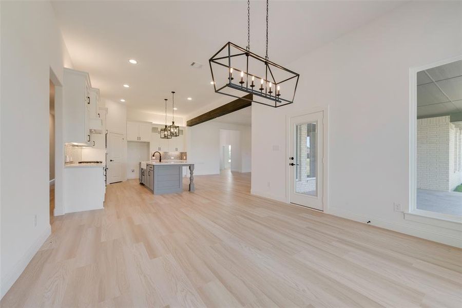 Unfurnished living room with sink, light hardwood / wood-style flooring, and a chandelier