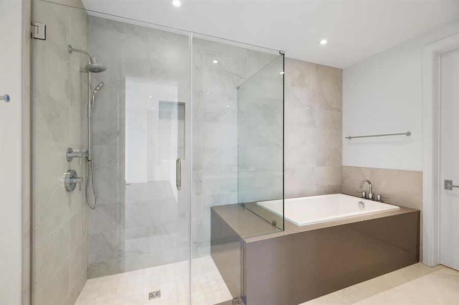 Separate step-in shower with hand held sprayer, bench seat and niche.  Tub and shower area with full tile surround.
