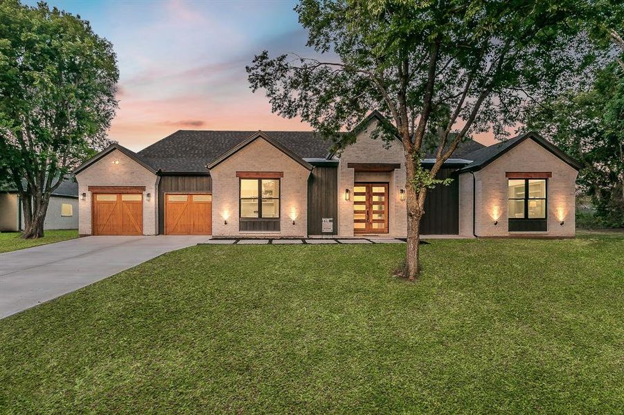 Modern farmhouse style home with a garage and a yard. Sod in photos is for visual aid purposes.