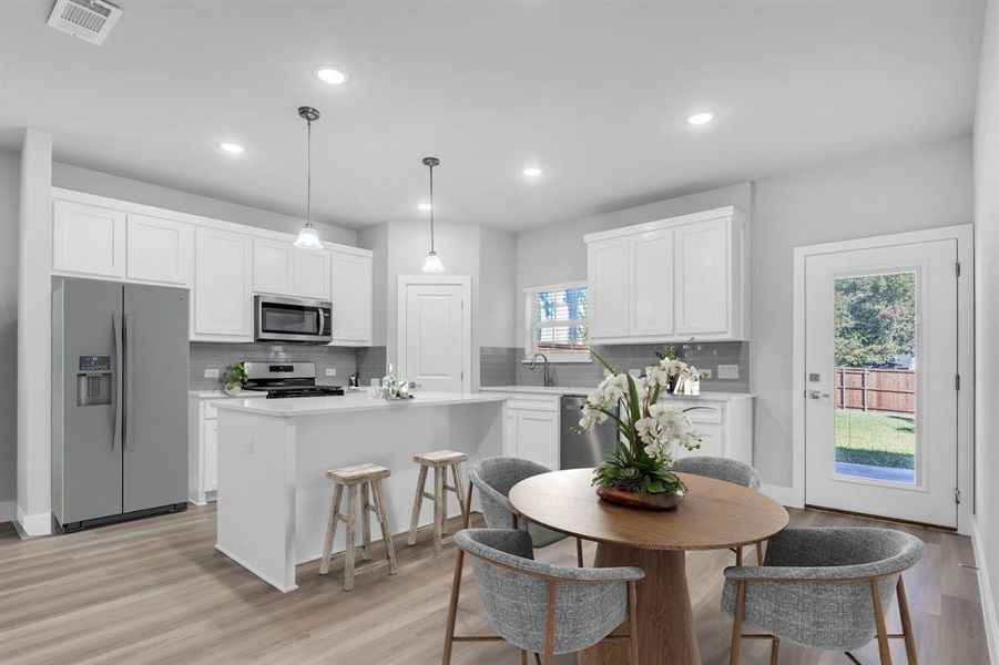 Kitchen with appliances with stainless steel finishes, decorative light fixtures, a center island, and a wealth of natural light