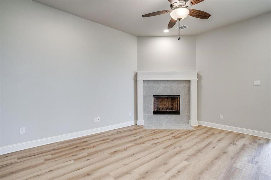 Unfurnished living room with a fireplace, light hardwood / wood-style flooring, and ceiling fan