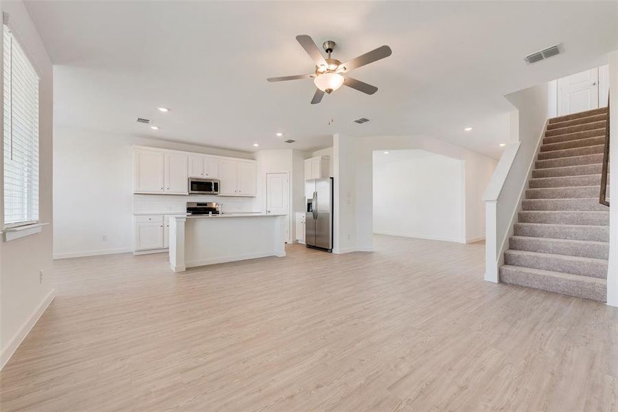 Unfurnished living room featuring light wood-type flooring and ceiling fan