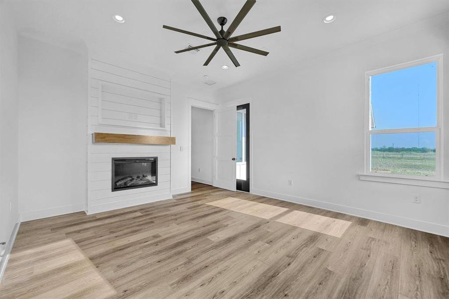 Unfurnished living room with ceiling fan, a fireplace, and light hardwood / wood-style flooring