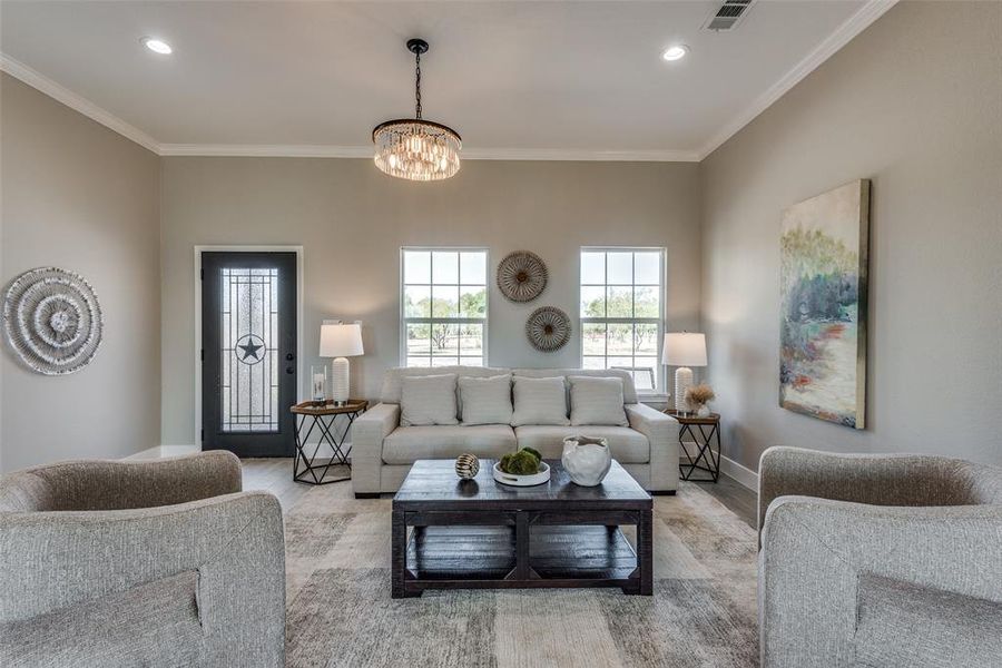 Living room with crown molding, a chandelier, and light hardwood / wood-style flooring