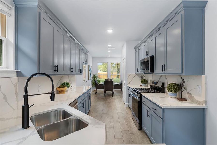 Kitchen featuring stainless steel appliances, backsplash, and light stone counters