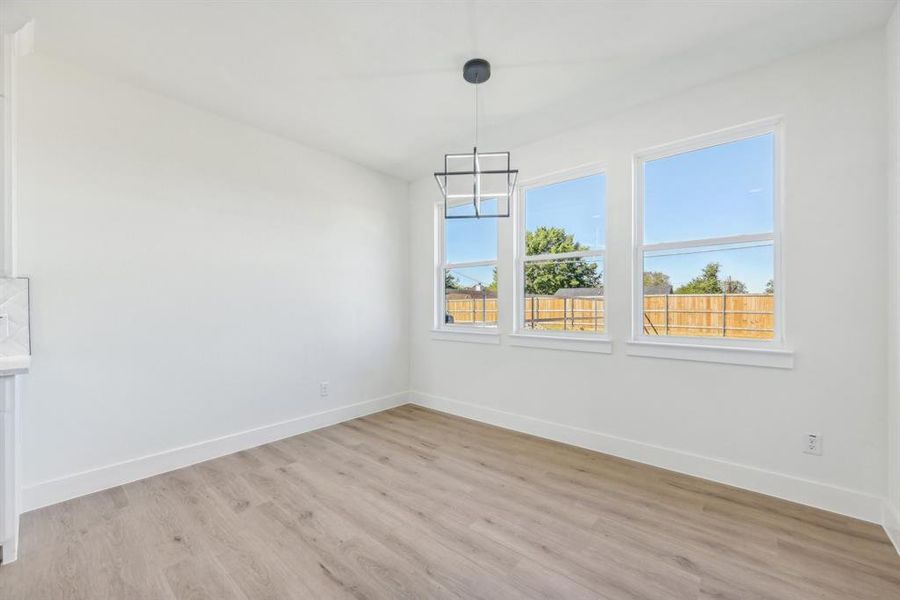 Spare room featuring a chandelier and light wood-type flooring