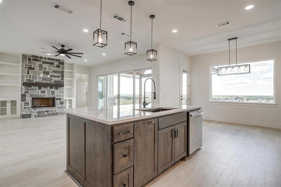 Kitchen featuring plenty of natural light, sink, ceiling fan, and a stone fireplace