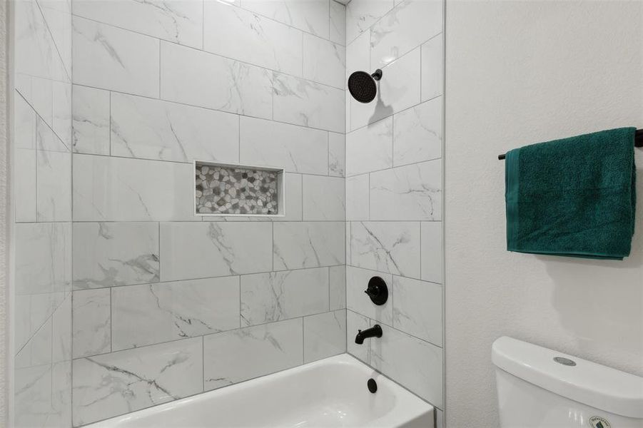 Bathroom with toilet and tiled shower / bath combo