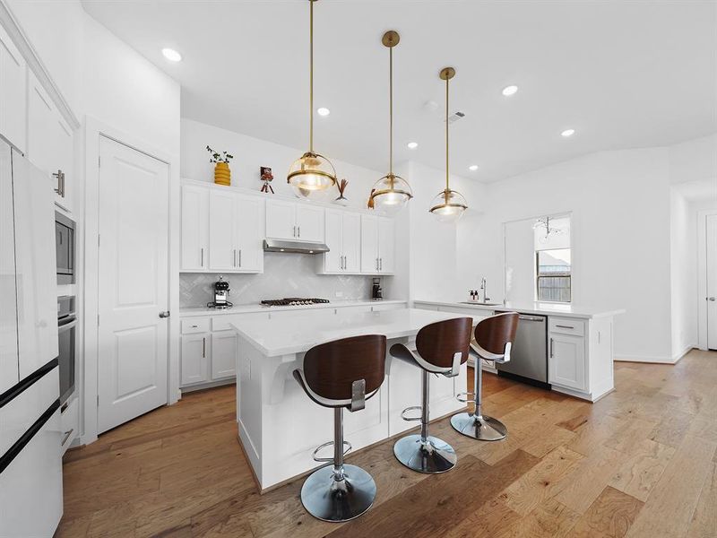 Enjoy cooking with the convenience of a 5-burner gas cooktop and plenty of storage space in the large pantry. The pendant lighting above the island creates a warm and inviting atmosphere, enhanced by luxurious gold fixtures.