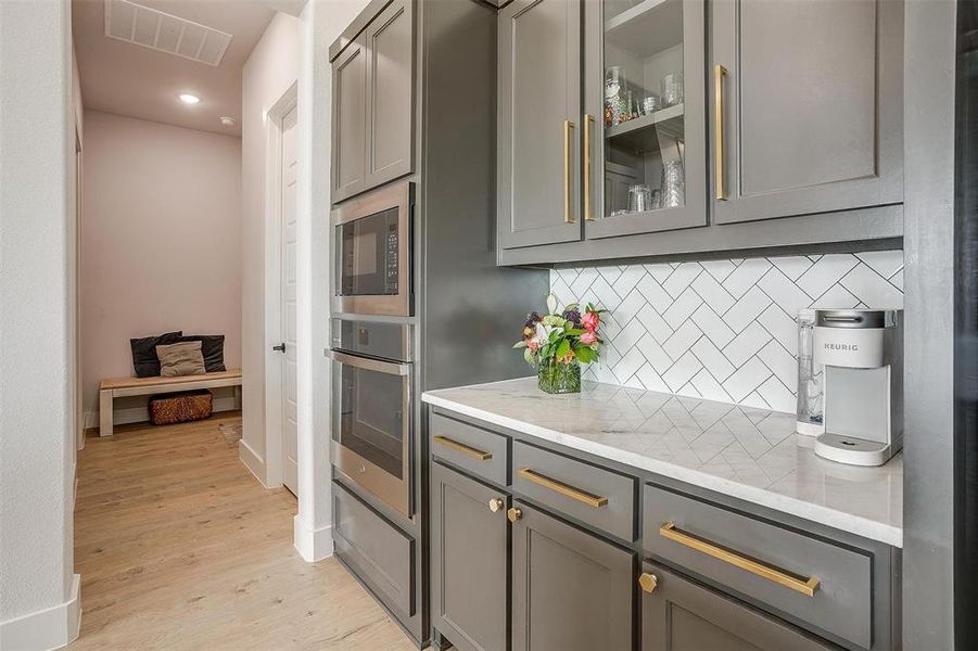 Kitchen featuring gray cabinetry, stainless steel appliances, light hardwood / wood-style floors, and tasteful backsplash