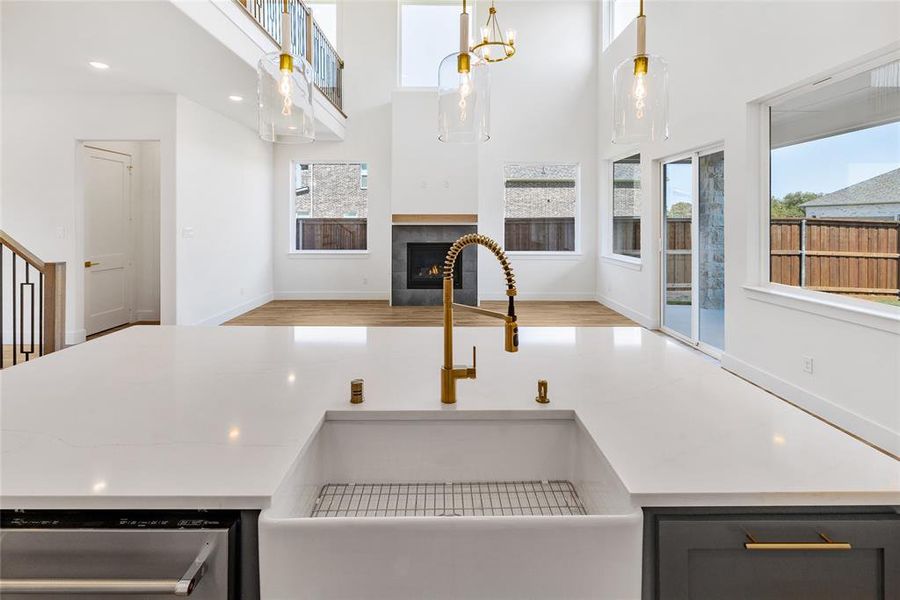 Kitchen featuring sink, a fireplace, stainless steel dishwasher, pendant lighting, and light hardwood / wood-style flooring