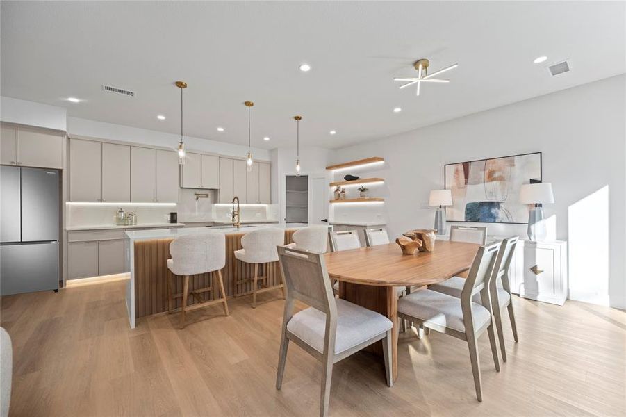 Dining space featuring ceiling fan, sink, and light wood-type flooring