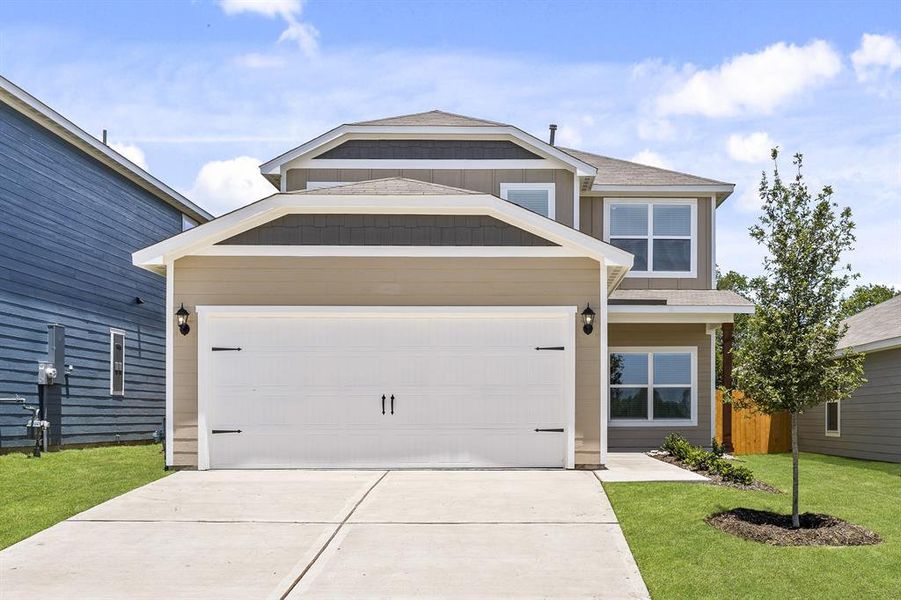 View of front of property with a garage and a front lawn