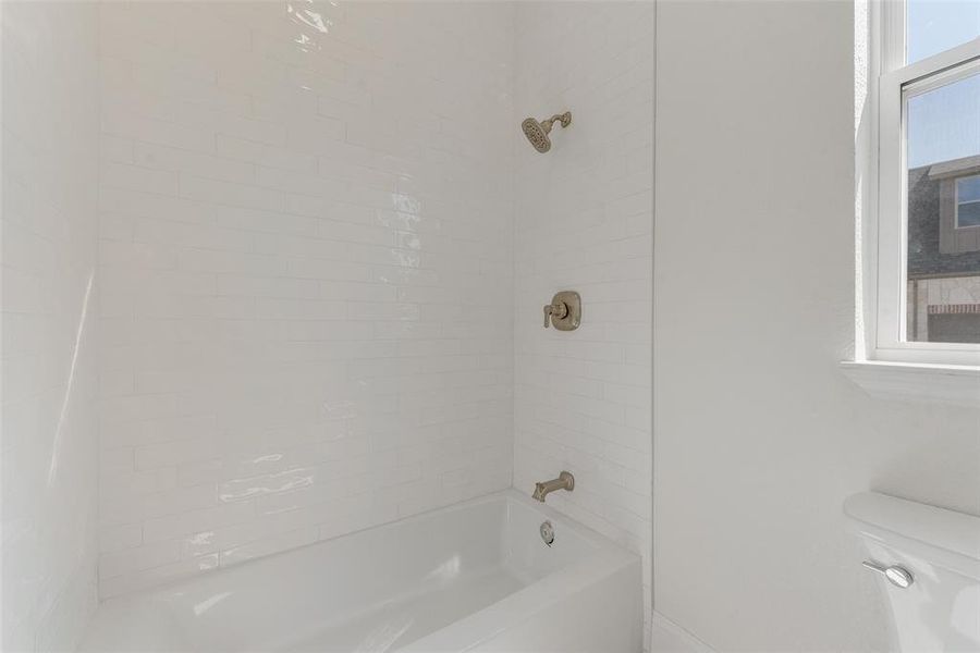 Bathroom featuring toilet and tiled shower / bath combo