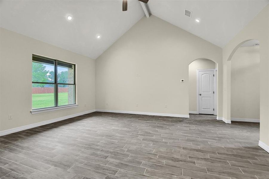 Unfurnished room with beam ceiling and high vaulted ceiling