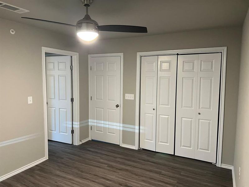 Unfurnished bedroom with dark wood-type flooring and ceiling fan