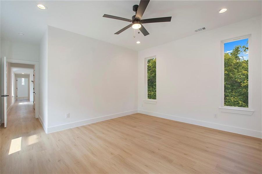 Empty room with a healthy amount of sunlight, ceiling fan, and light hardwood / wood-style flooring