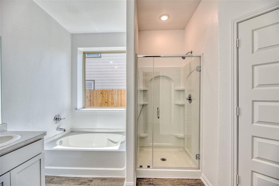 The ensuite bathroom features an oversized tub, perfect for indulging in a relaxing soak after a long day. Alongside of the tub, a walk-in shower stands ready to provide a refreshing rinse, offering both convenience and luxury for daily pampering routines.
