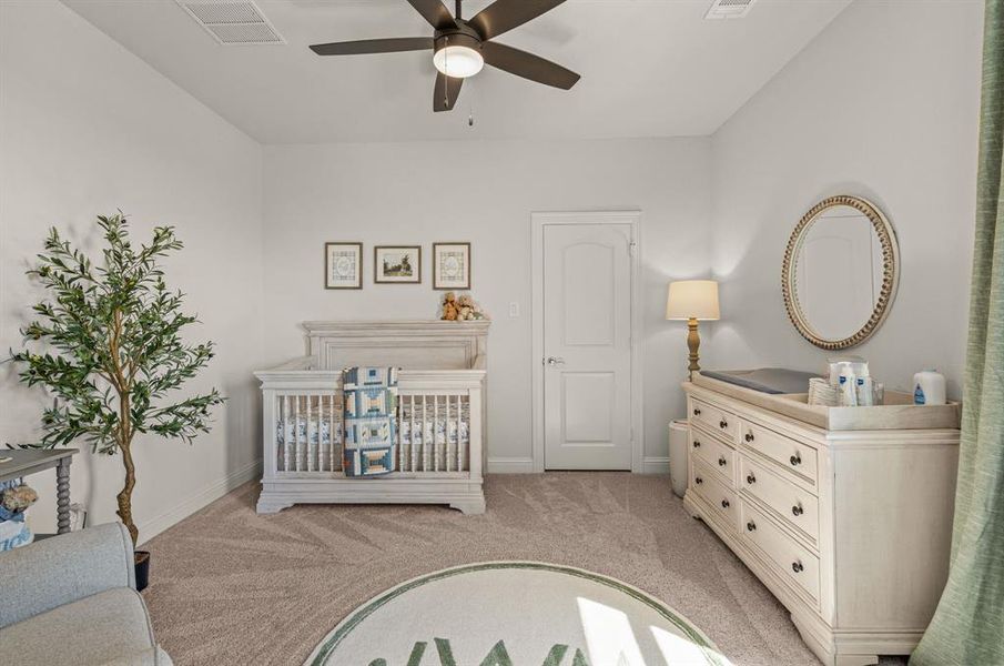 Bedroom featuring ceiling fan, light colored carpet, and a crib